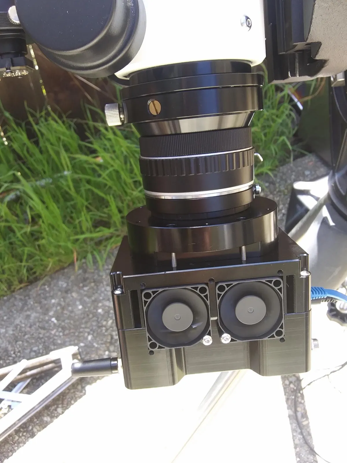 A prototype cooled camera with twin fans attached to a lens on a telescope outdoors