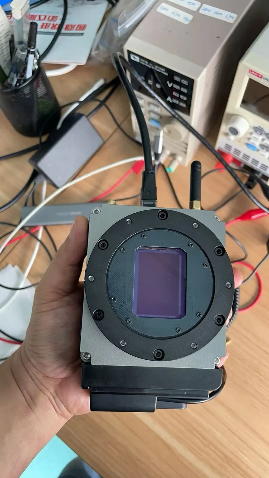 A hand holding the first C42 prototype camera with its full-frame sensor exposed