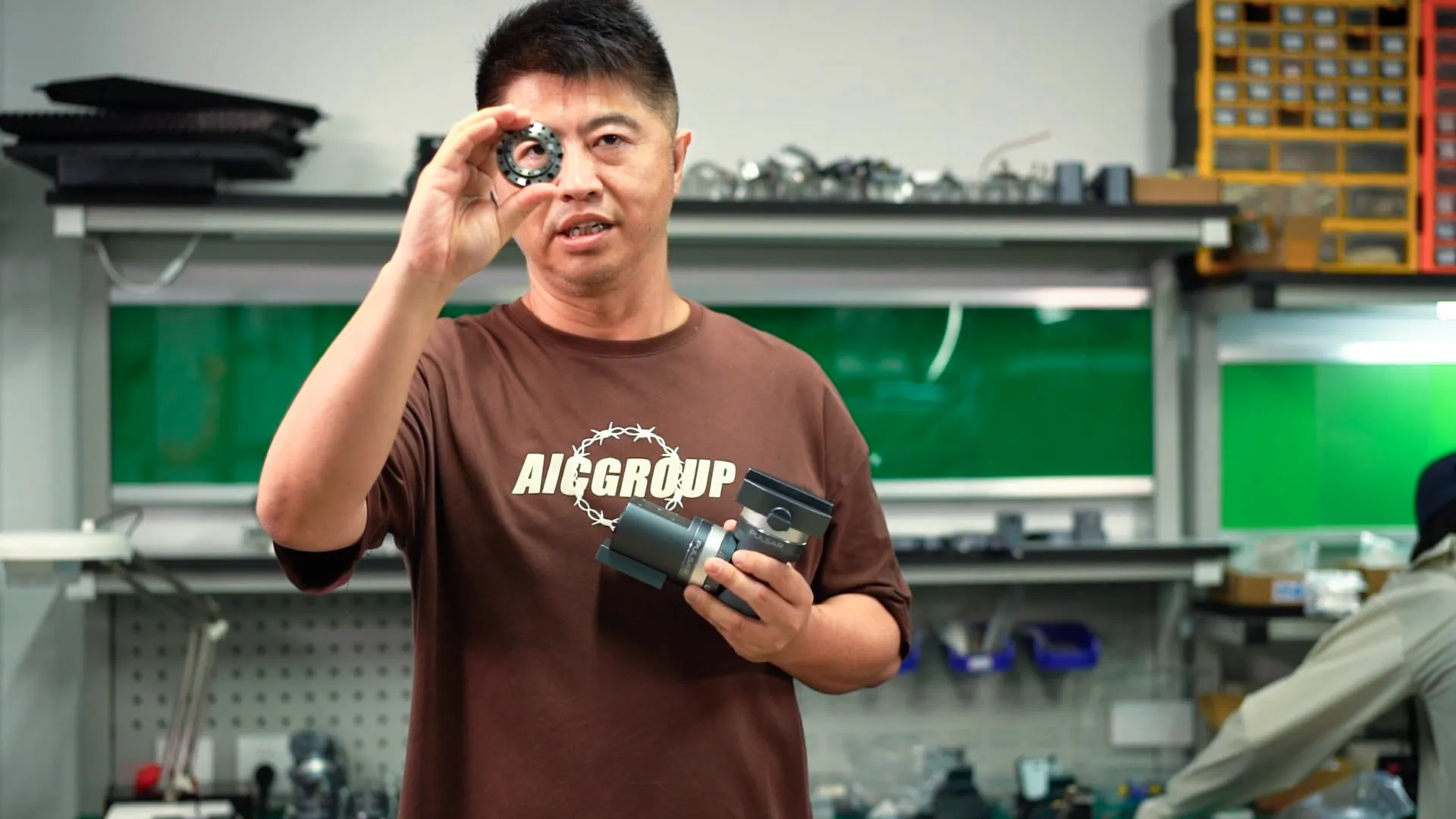 An ArcBlue engineer holding a compact harmonic drive component beside a Pulsar mount in the workshop.